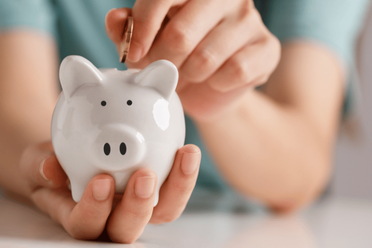 Female hand putting money into piggy bank for saving money